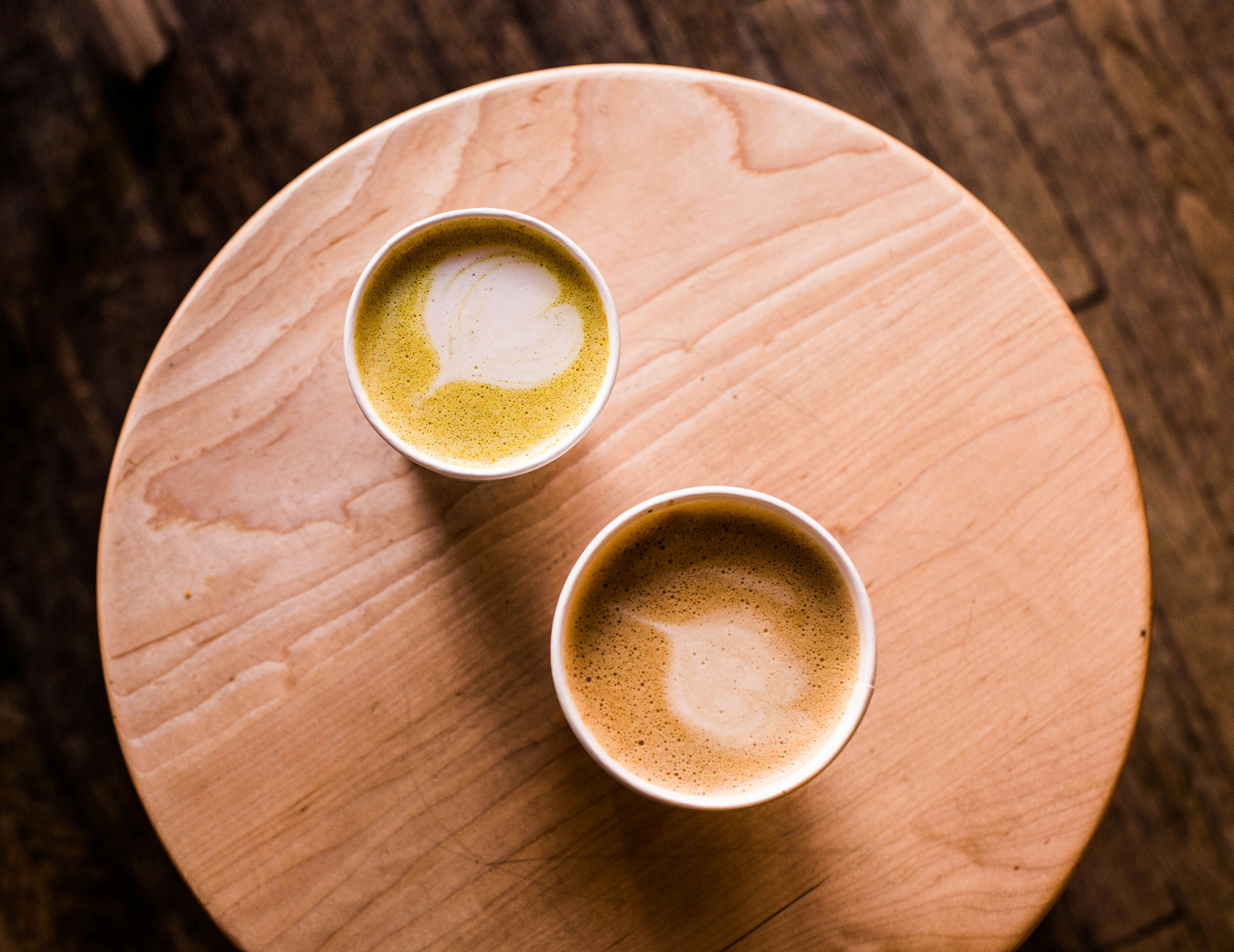 two beige cappuccinos on beige wooden stool